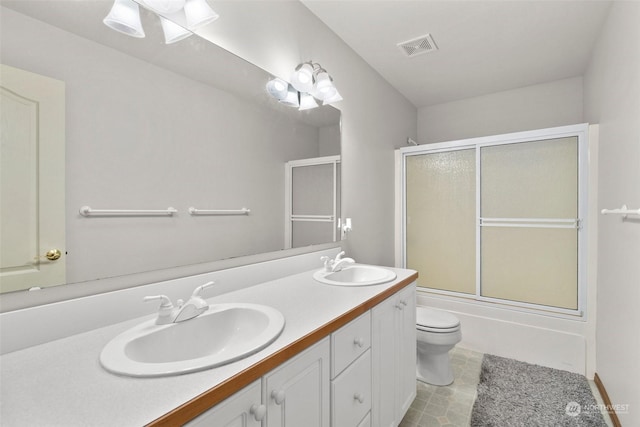 full bathroom with bath / shower combo with glass door, vanity, and toilet