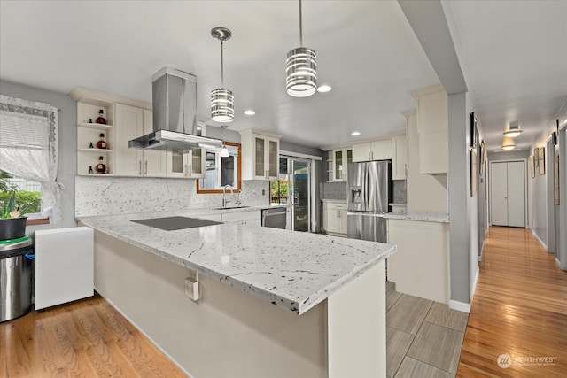 kitchen with kitchen peninsula, island exhaust hood, hanging light fixtures, light hardwood / wood-style floors, and stainless steel appliances