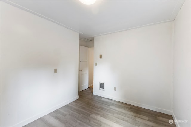 empty room with crown molding and light hardwood / wood-style flooring