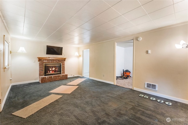 unfurnished living room with a brick fireplace and dark carpet