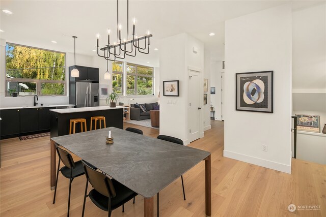 dining space with light wood-type flooring, sink, and a chandelier