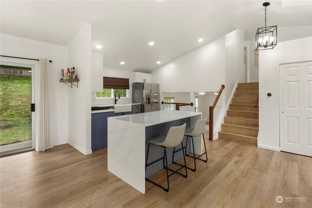 27705 23rd Ave S, Federal Way, WA 98003 - kitchen featuring lofted ceiling, a kitchen bar, stainless steel refrigerator with ice dispenser, and light wood-style floors