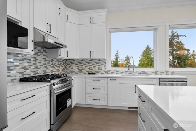 kitchen with appliances with stainless steel finishes, white cabinets, sink, and backsplash