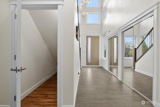 hallway featuring dark wood-type flooring, a notable chandelier, and plenty of natural light