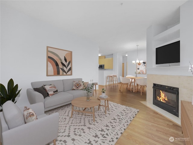 living room with an inviting chandelier, light hardwood / wood-style floors, and a tile fireplace