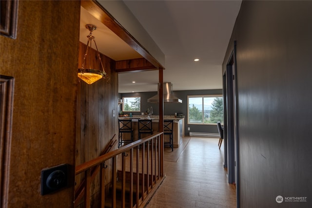 corridor with wood walls, light hardwood / wood-style floors, and baseboard heating