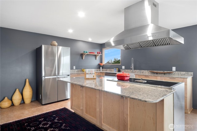 kitchen featuring a kitchen island, freestanding refrigerator, light stone countertops, ventilation hood, and light brown cabinetry