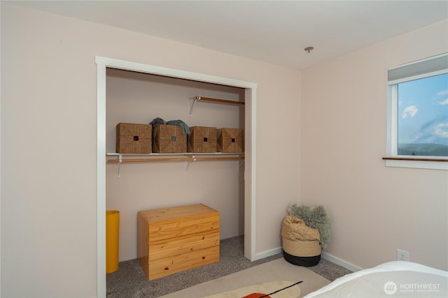 carpeted bedroom with a closet and baseboards