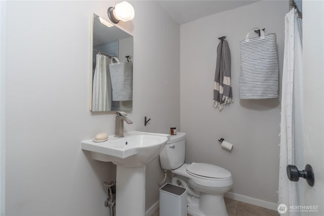 bathroom featuring tile patterned flooring, baseboards, and toilet