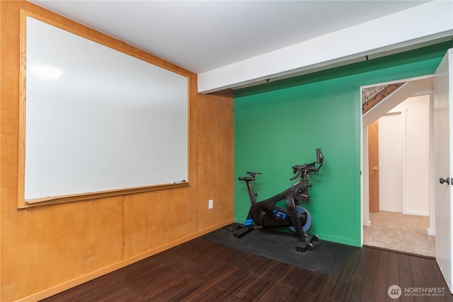 exercise area featuring arched walkways and wood finished floors