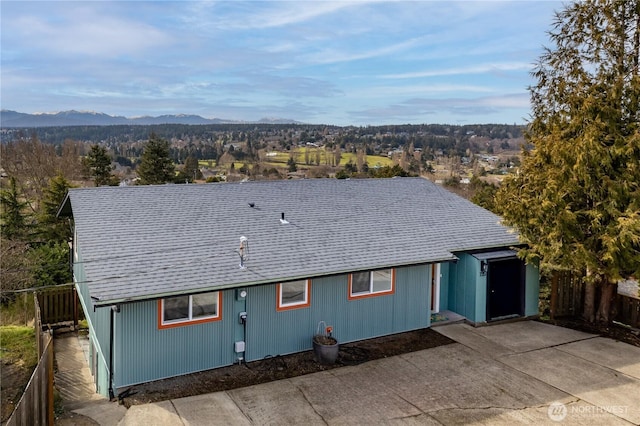 view of front of home featuring a forest view, a mountain view, and roof with shingles