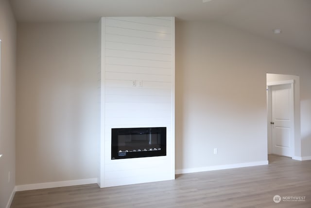 unfurnished living room with light hardwood / wood-style floors, lofted ceiling, and a fireplace