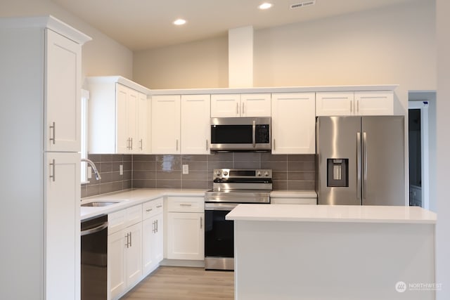 kitchen featuring appliances with stainless steel finishes, white cabinets, sink, and vaulted ceiling