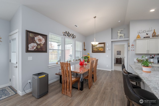 dining space featuring light hardwood / wood-style flooring and vaulted ceiling