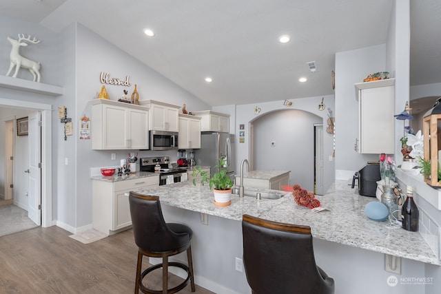 kitchen featuring appliances with stainless steel finishes, sink, kitchen peninsula, and a kitchen bar