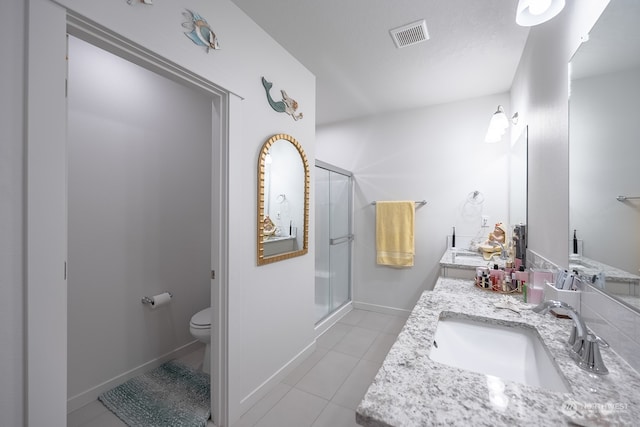 bathroom featuring vanity, a shower with shower door, toilet, and tile patterned floors