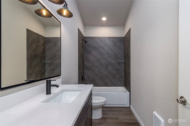 full bathroom with toilet, tiled shower / bath, hardwood / wood-style flooring, and vanity