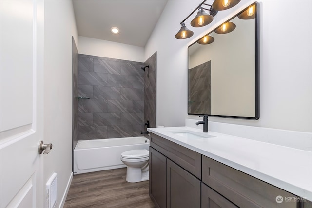 full bathroom with toilet, tiled shower / bath, hardwood / wood-style flooring, and vanity