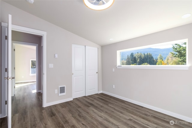 unfurnished bedroom with dark wood-type flooring, a closet, and lofted ceiling