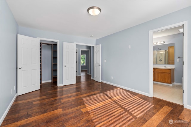 unfurnished bedroom with connected bathroom, a closet, a spacious closet, and dark hardwood / wood-style flooring