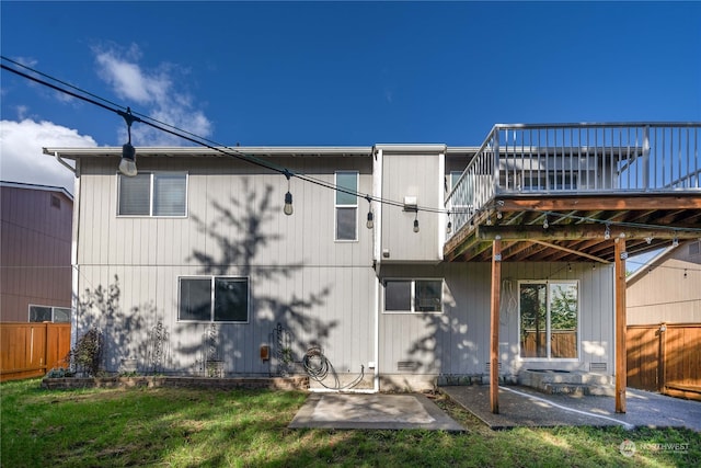 back of property featuring a wooden deck, a yard, and a patio