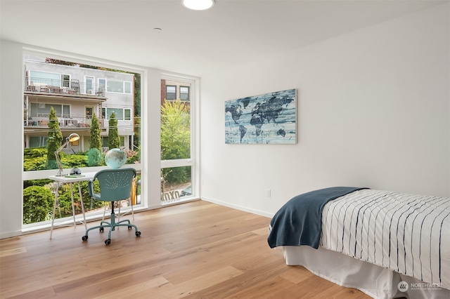 bedroom with a wall of windows and light hardwood / wood-style flooring