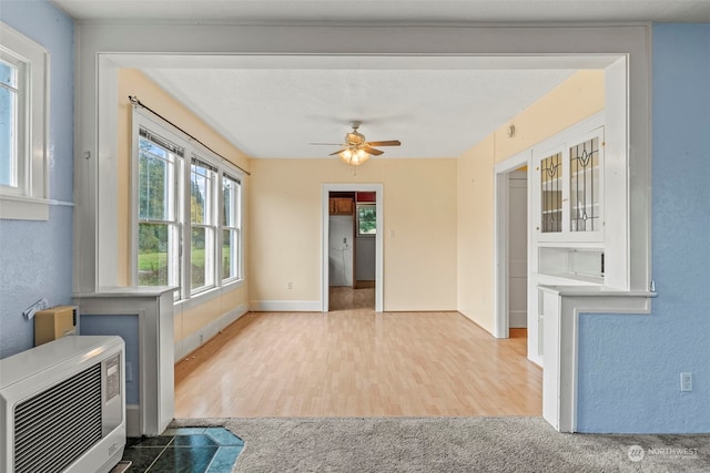 unfurnished living room featuring hardwood / wood-style flooring, heating unit, and ceiling fan