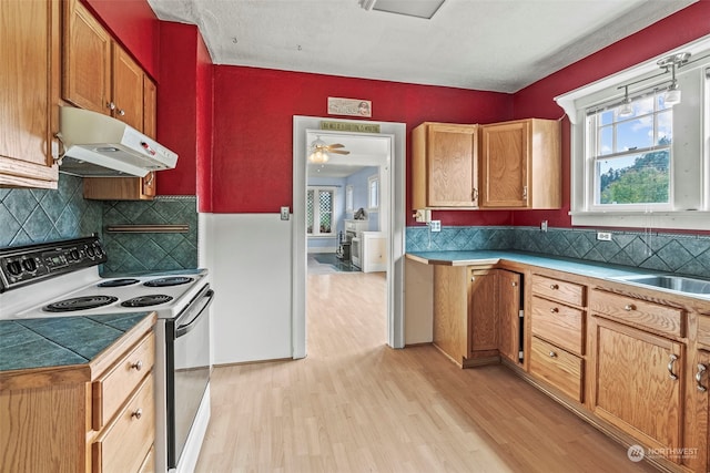 kitchen with electric range, tasteful backsplash, light wood-type flooring, and ceiling fan