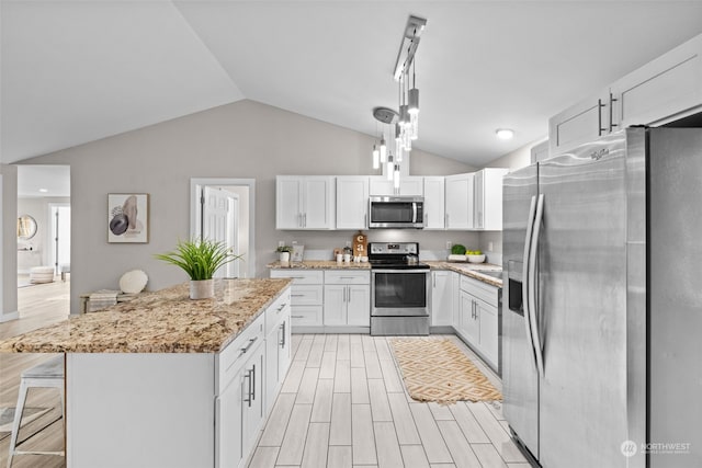 kitchen featuring stainless steel appliances, white cabinetry, hanging light fixtures, a kitchen island, and lofted ceiling