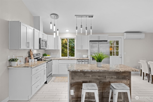 kitchen featuring stainless steel appliances, a kitchen bar, hanging light fixtures, a wall mounted air conditioner, and a center island