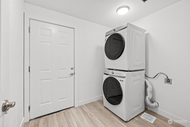 washroom with light hardwood / wood-style floors and stacked washer / dryer