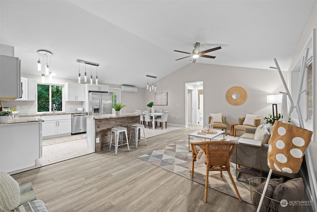 living room featuring sink, a wall mounted air conditioner, lofted ceiling, ceiling fan, and light hardwood / wood-style flooring