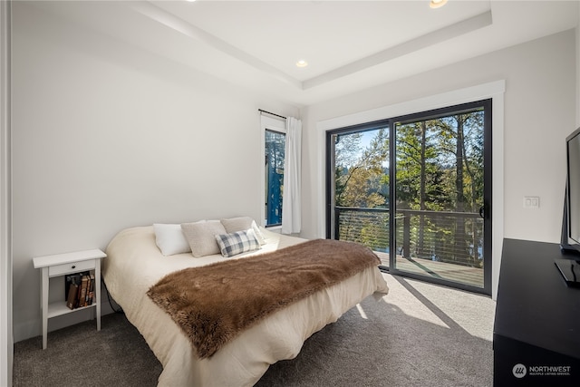 carpeted bedroom with access to exterior and a raised ceiling