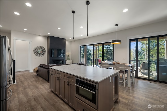 kitchen featuring light stone counters, hanging light fixtures, stainless steel appliances, and dark hardwood / wood-style floors