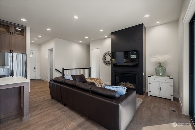 living room featuring a large fireplace and dark hardwood / wood-style flooring