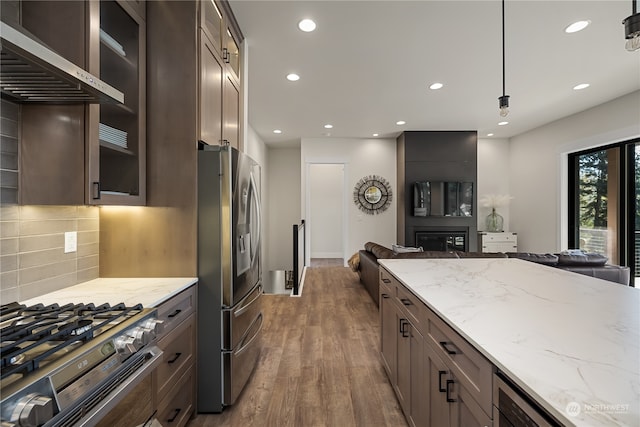 kitchen featuring decorative backsplash, light stone counters, appliances with stainless steel finishes, hardwood / wood-style flooring, and decorative light fixtures