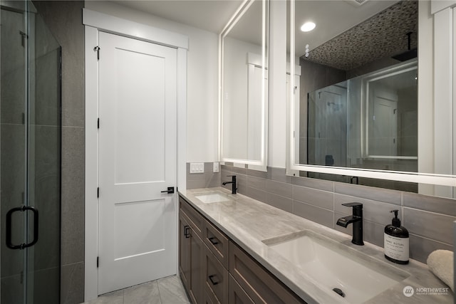 bathroom with a shower with door, vanity, tile walls, and backsplash