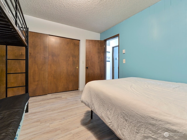 bedroom featuring a closet, a textured ceiling, and light wood-type flooring