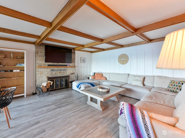 living room featuring beamed ceiling, coffered ceiling, a fireplace, and light wood-type flooring