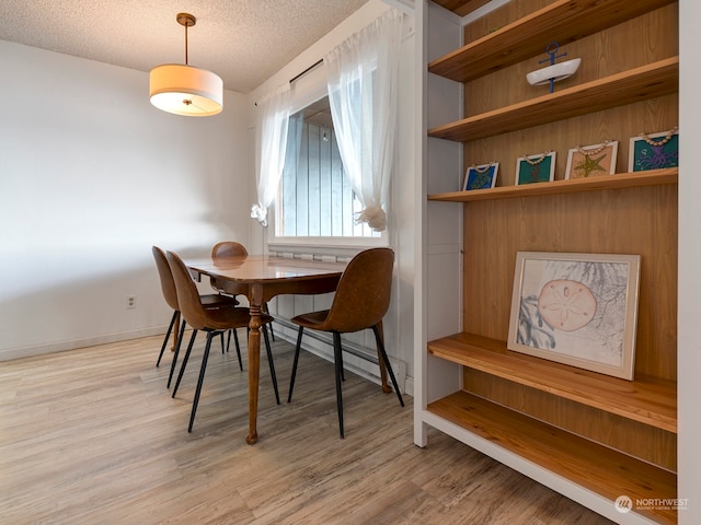 dining area with light hardwood / wood-style flooring and a textured ceiling