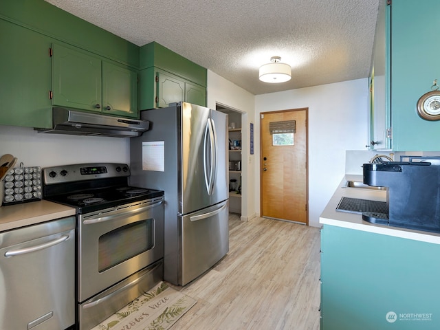 kitchen with a textured ceiling, appliances with stainless steel finishes, and light hardwood / wood-style flooring