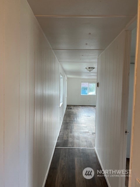 hall with wood walls and dark wood-type flooring