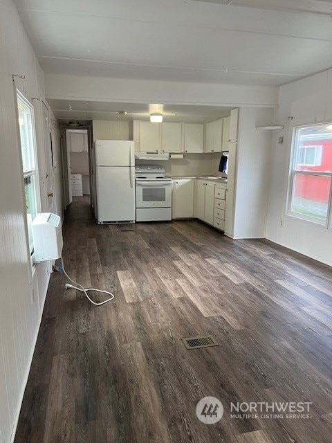 105 Cox Unit 12, Arlington, WA 98223 - kitchen with white appliances, dark wood-style floors, a wall unit AC, light countertops, and white cabinets