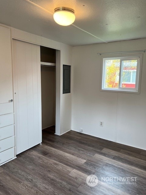 105 Cox Unit 12, Arlington, WA 98223 - unfurnished bedroom featuring electric panel, dark wood-type flooring, a closet, and a textured ceiling