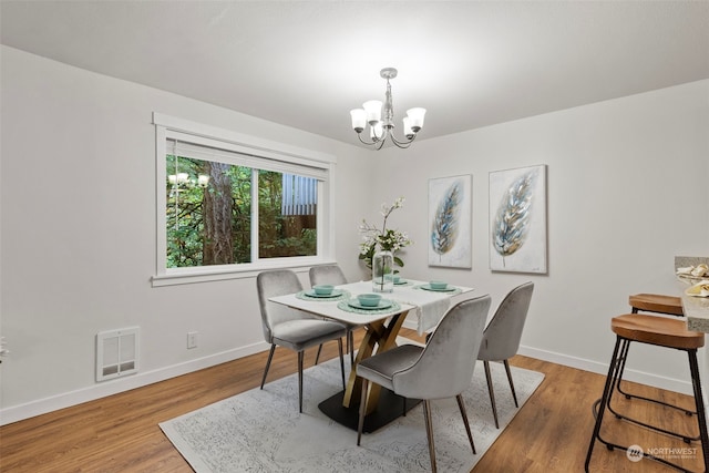 dining room with light hardwood / wood-style flooring and an inviting chandelier