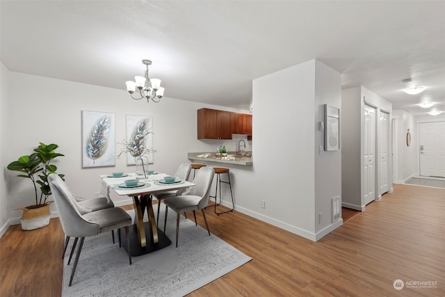 dining room with light hardwood / wood-style floors, a chandelier, and sink