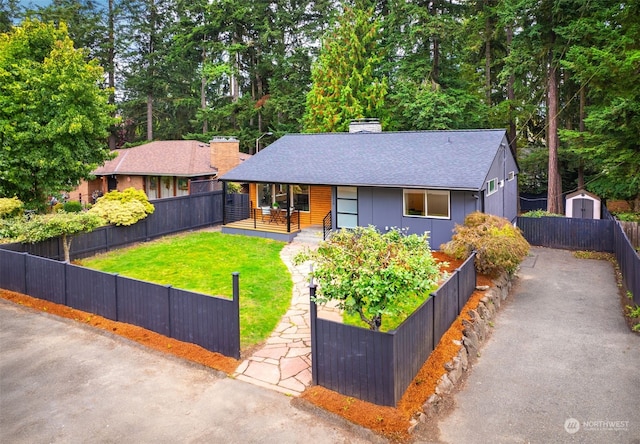 view of front of house with a storage shed and a front yard