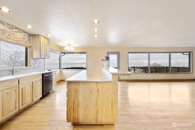 kitchen with a breakfast bar, dishwasher, a center island, light brown cabinetry, and light wood-type flooring