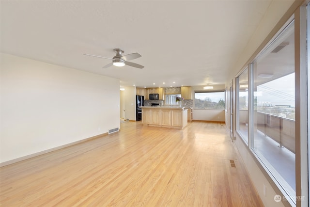 unfurnished living room featuring ceiling fan and light hardwood / wood-style flooring