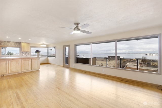 unfurnished living room with ceiling fan, sink, and light hardwood / wood-style floors